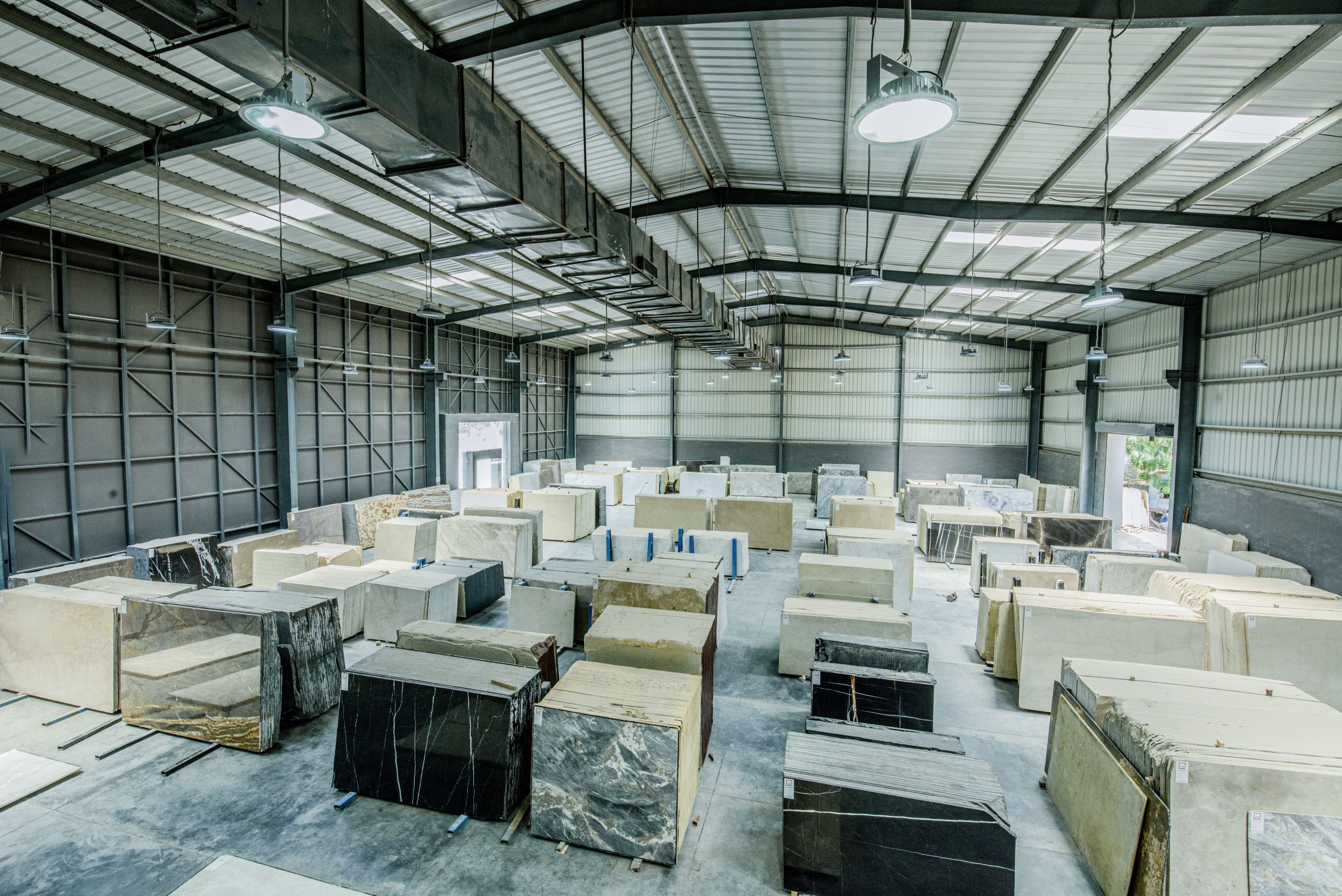 Expansive warehouse filled with large stone slabs for industrial use.
